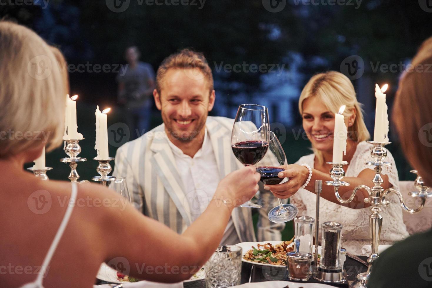 Lächeln und gute Laune. Gruppe von Freunden in der eleganten Kleidung haben ein luxuriöses Abendessen foto