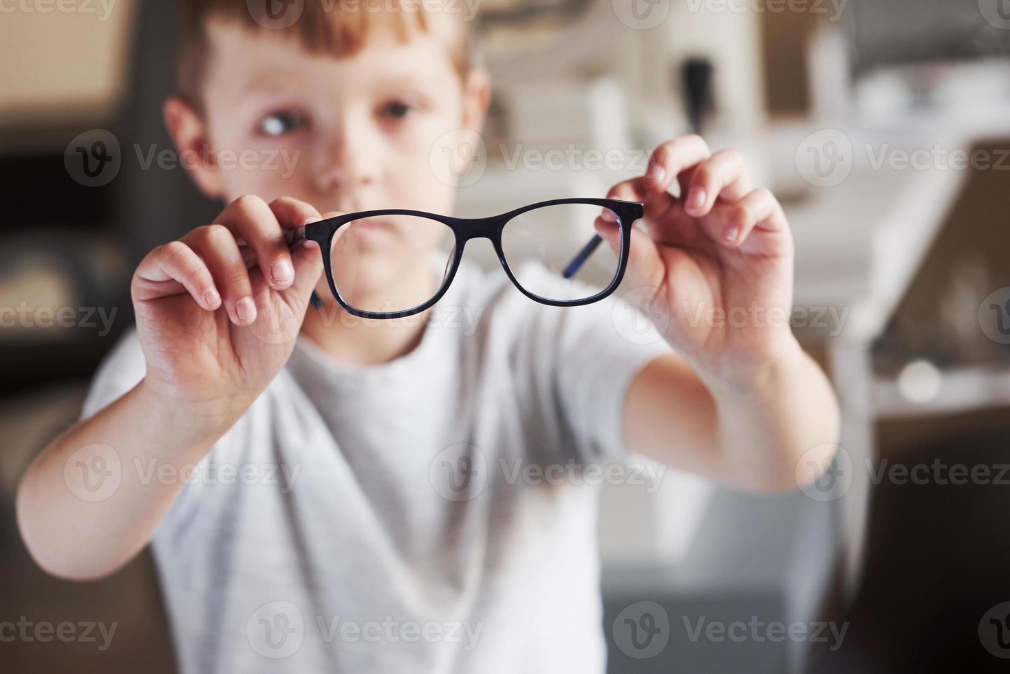 fokussiertes Foto. kleiner Junge hält seine neue Brille in der Arztpraxis foto