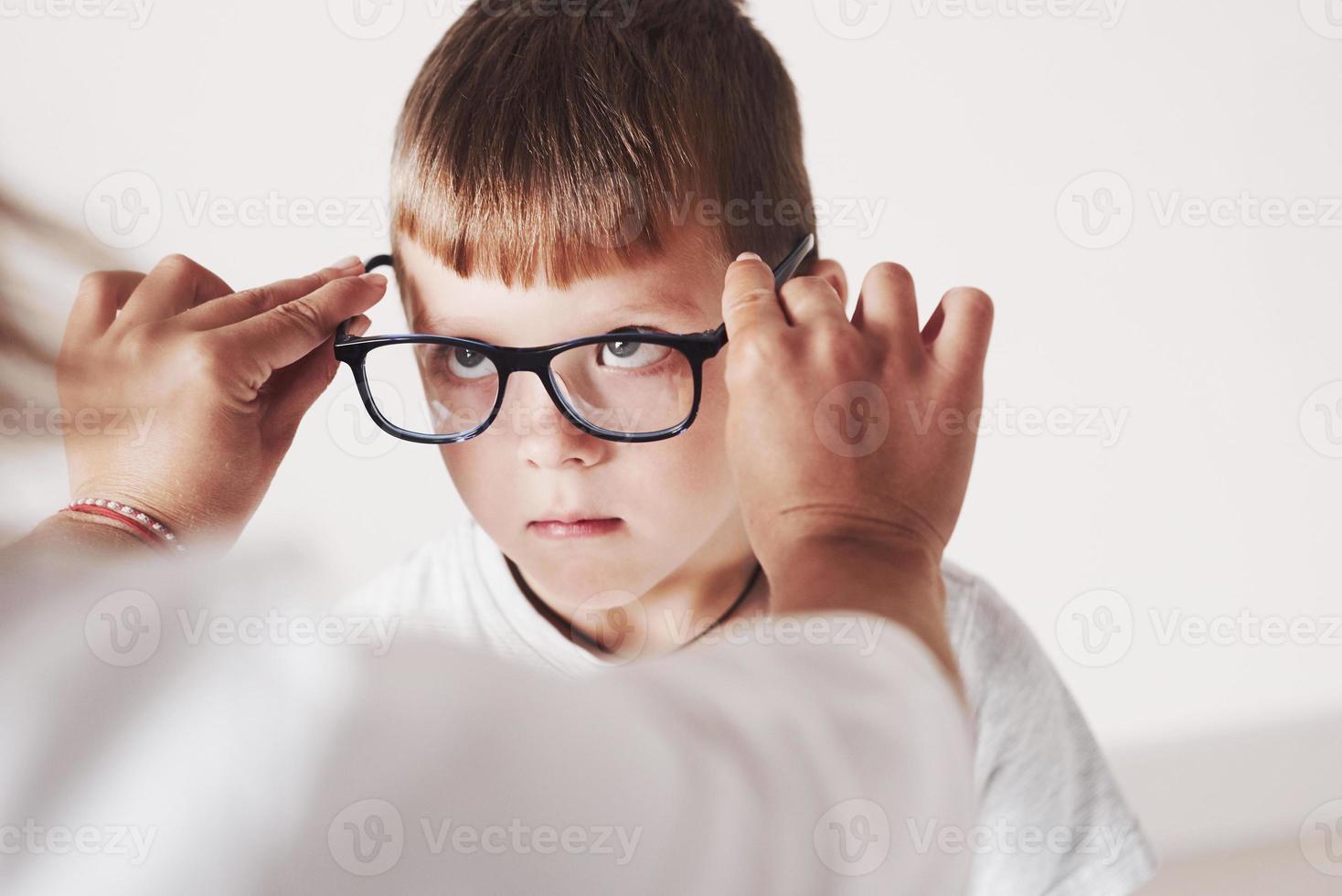 gib mir deinen Blick auf. Arzt gibt dem Kind eine neue schwarze Brille für seine Vision foto