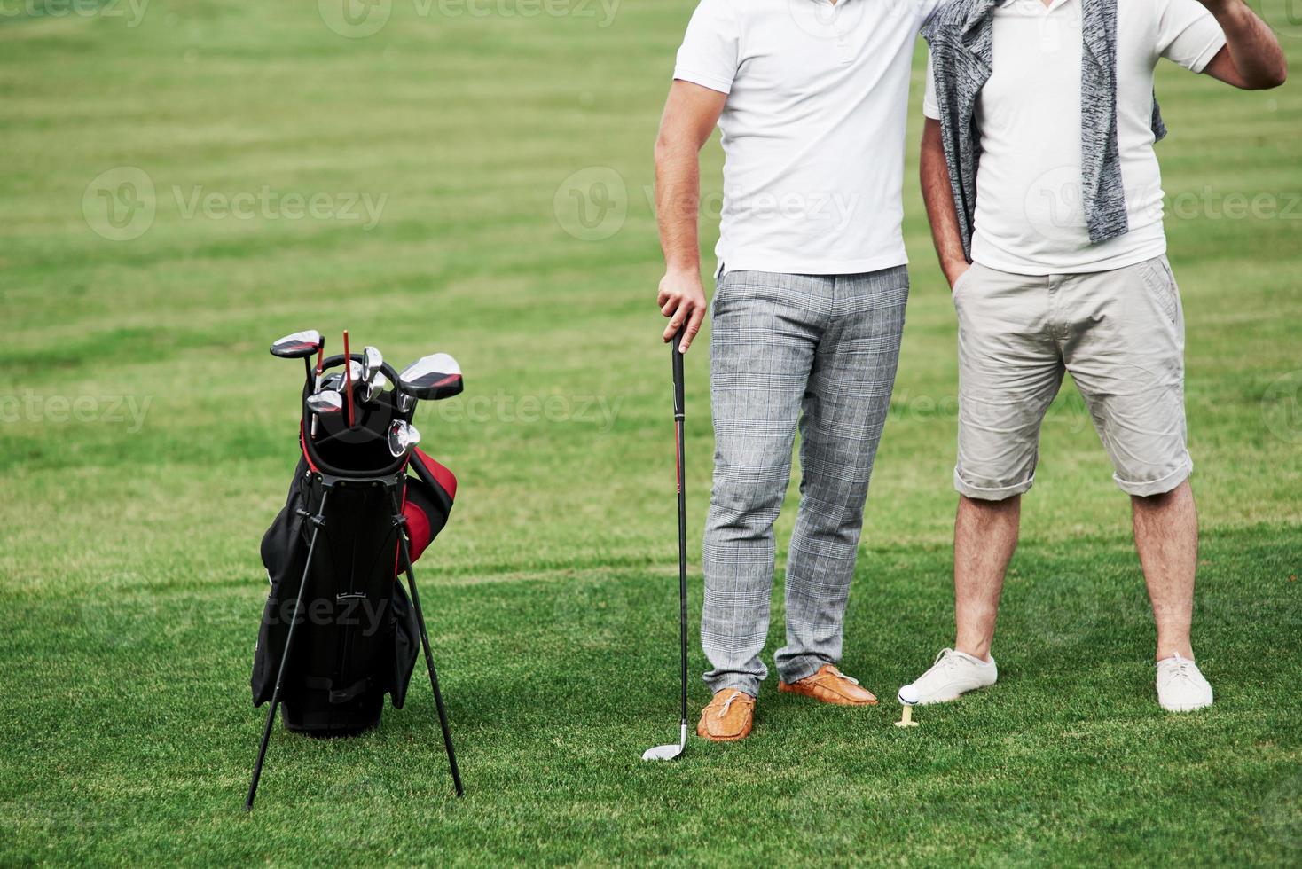 Vorderansicht. Ausgeschnittenes Foto von zwei Freunden auf dem Sportplatz mit Golfausrüstung