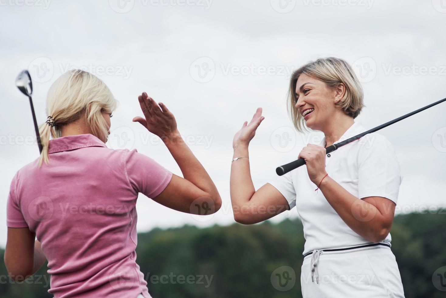 zwei Golfspielerinnen geben High Five im Hintergrund von wunderschönen grünen Wäldern foto