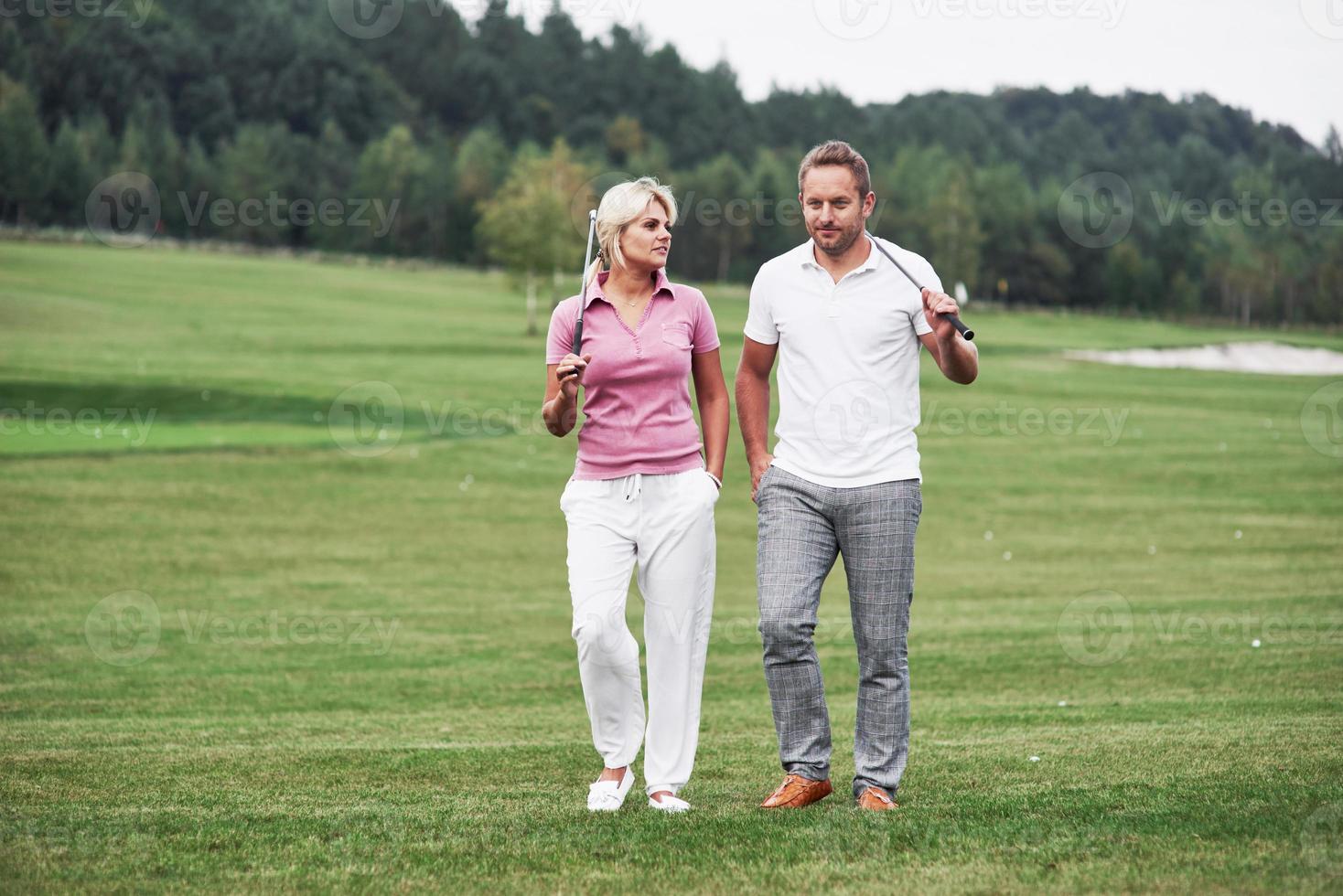 ein paar Golfspieler mit Stöcken in den Händen, die auf dem Rasen laufen foto