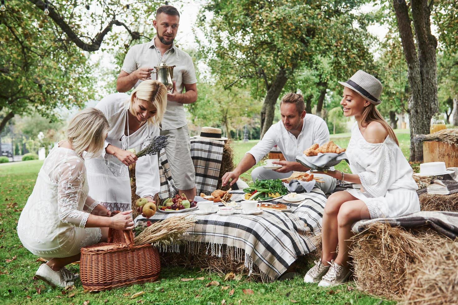 Ruhe und gute Laune. Eine Gruppe erwachsener Freunde ruht sich zum Abendessen im Hinterhof des Restaurants aus und unterhält sich foto