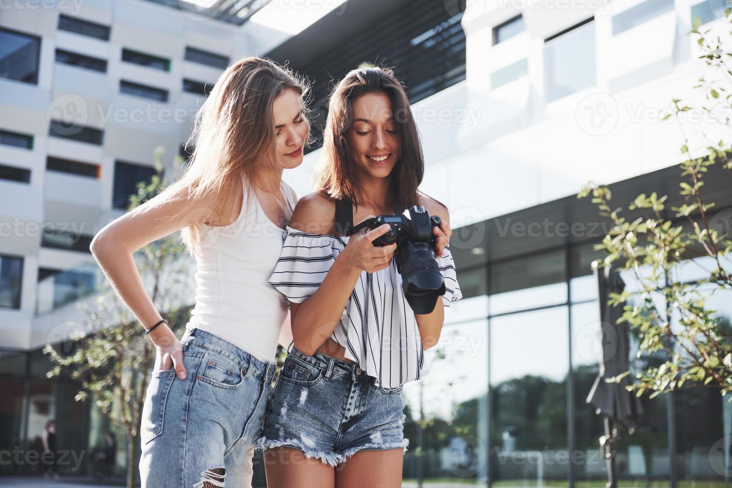 zwei hübsche hübsche Freundinnen des Mädchens mit der Kamera machen zusammen Fotos und gehen in der Stadt spazieren