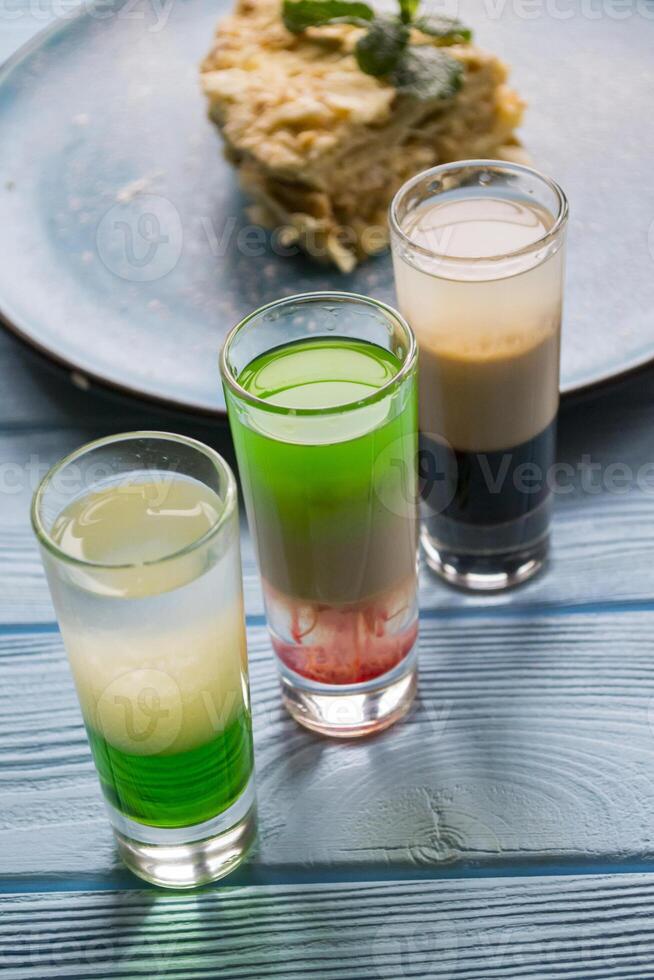 das Cocktails und Napoleon Kuchen auf ein Blau hölzern Tisch. foto