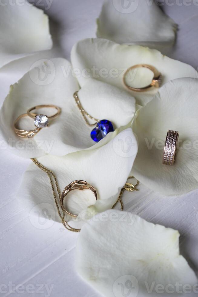 Halskette und Gold Ringe auf ein Weiß Blütenblätter von Rosen. foto