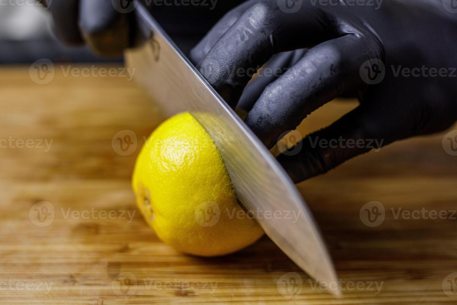 Person mit schwarz Handschuhe Schneiden Zitrone im Hälfte foto