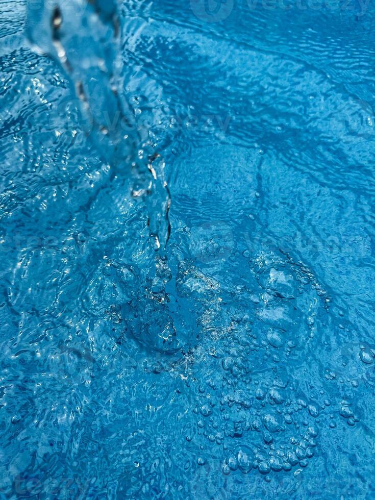 Hintergrund dynamisch Spritzen von klar Wasser Erstellen wirbelnd Welle im Blau Wasser mit Tröpfchen suspendiert im Bewegung. sauber Wasser Konzept. foto
