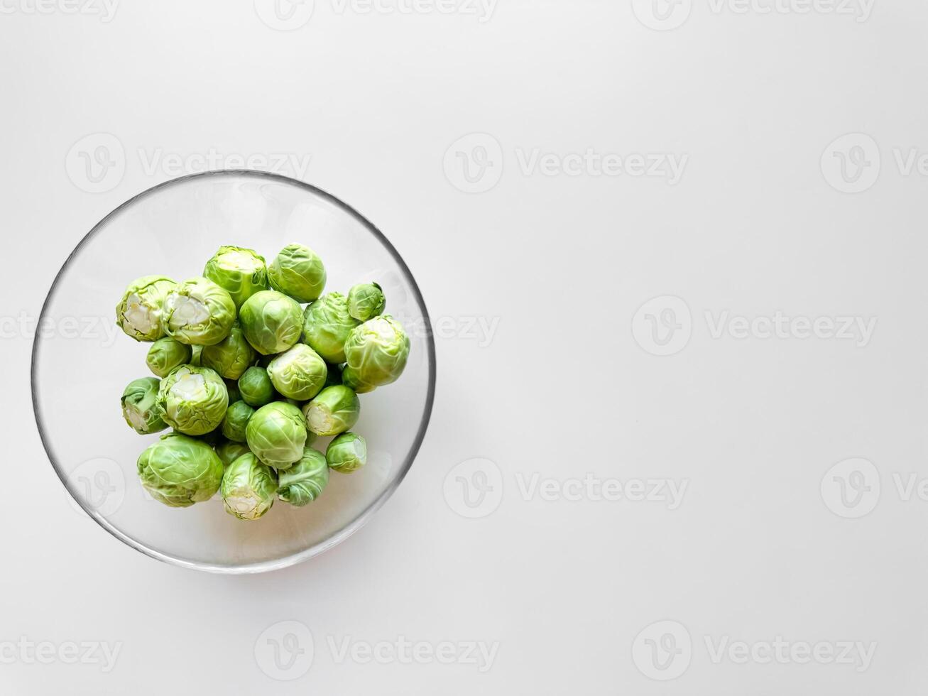 Brüssel Sprossen im transparent Glas Schüssel auf Weiß Hintergrund mit reichlich Raum zum Text, gesund Essen Konzept. foto