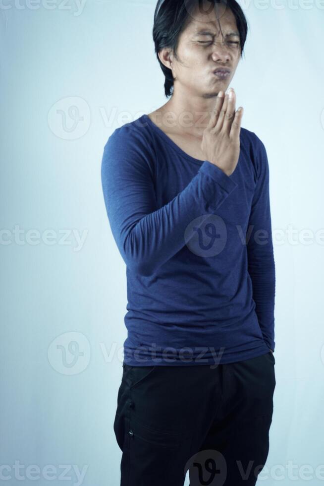 das Gestank ist scharf. gut aussehend jung asiatisch Mann Falten seine Nase im der Ekel. halten Ihre Atem mit unangenehm Ausdrücke. foto