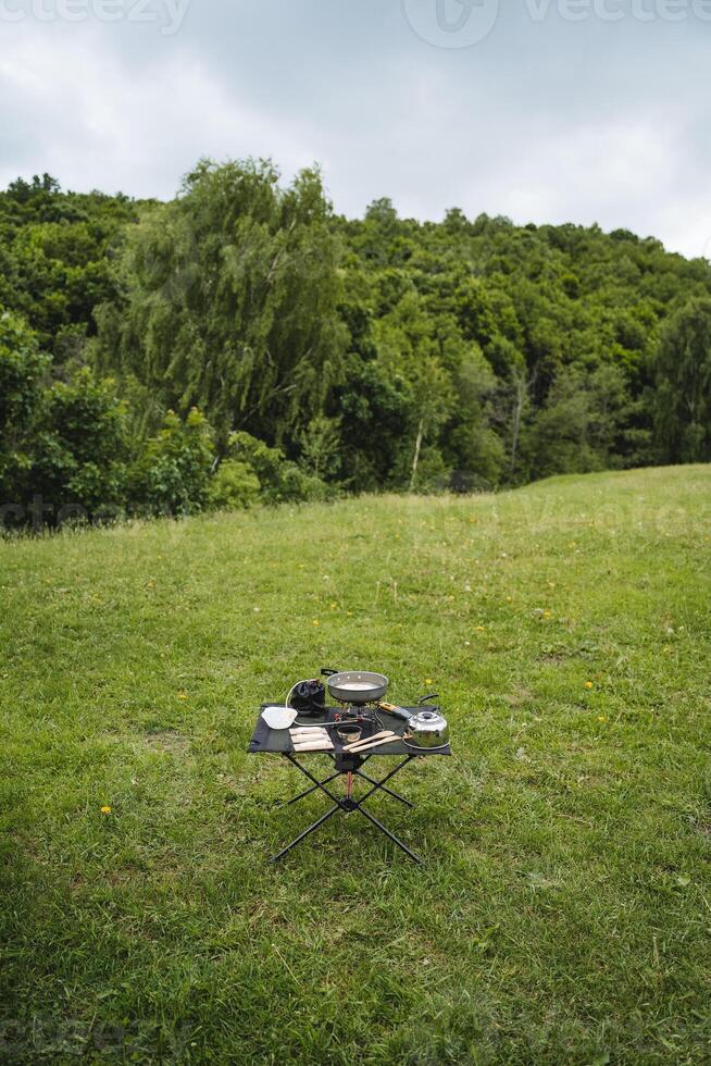 falten kompakt Tabelle zum Camping im Natur, Tourist Essen auf ein Wanderung, Geschirr zum Kochen, fertig Frühstück von ein Tourist. foto