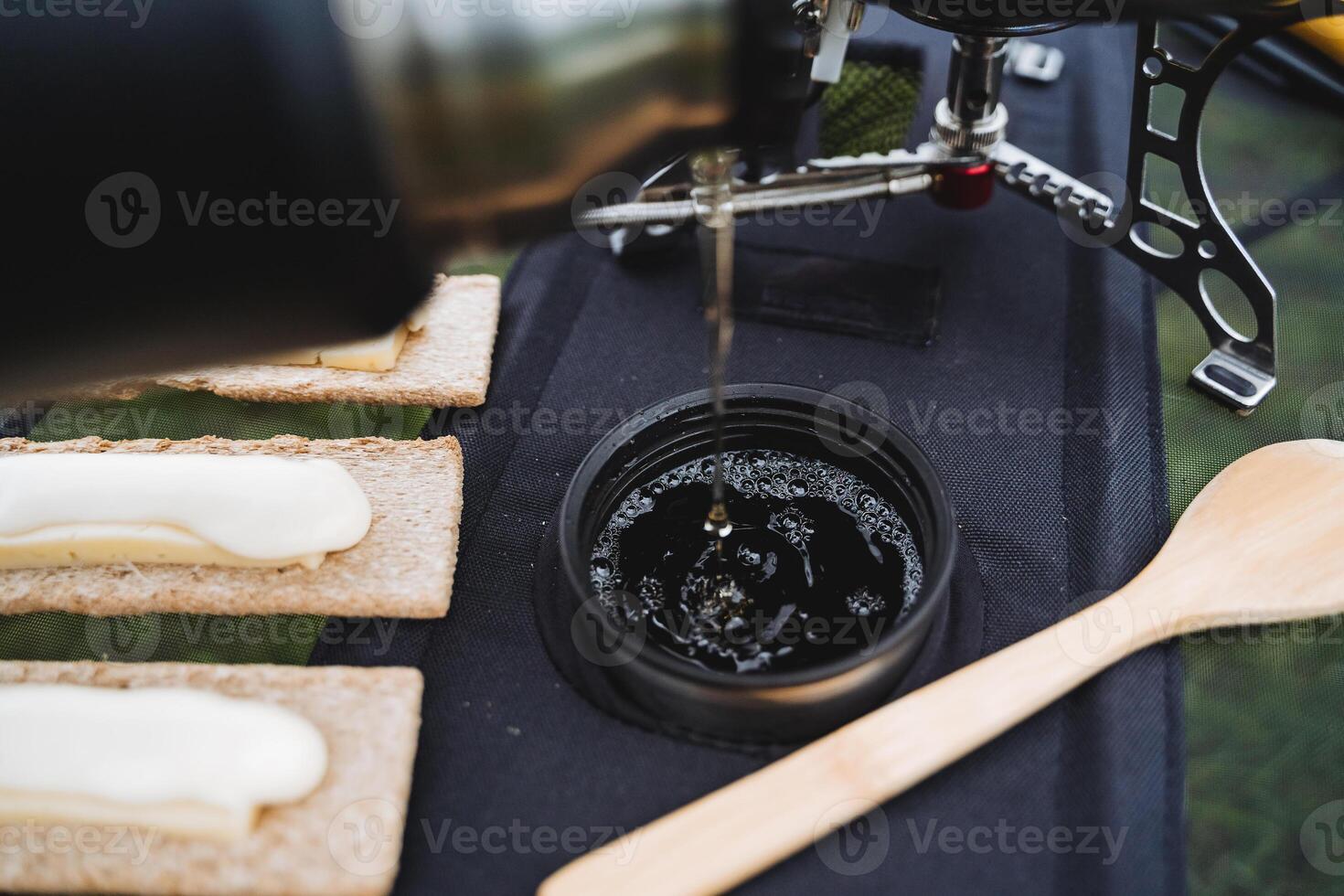 Tee gießt in ein Becher auf oben von ein Laib von Wasser Luftblasen Schaum Aussicht von über, ein heiß trinken von ein Thermosflasche, Lager Essen, Tourist Teller. foto