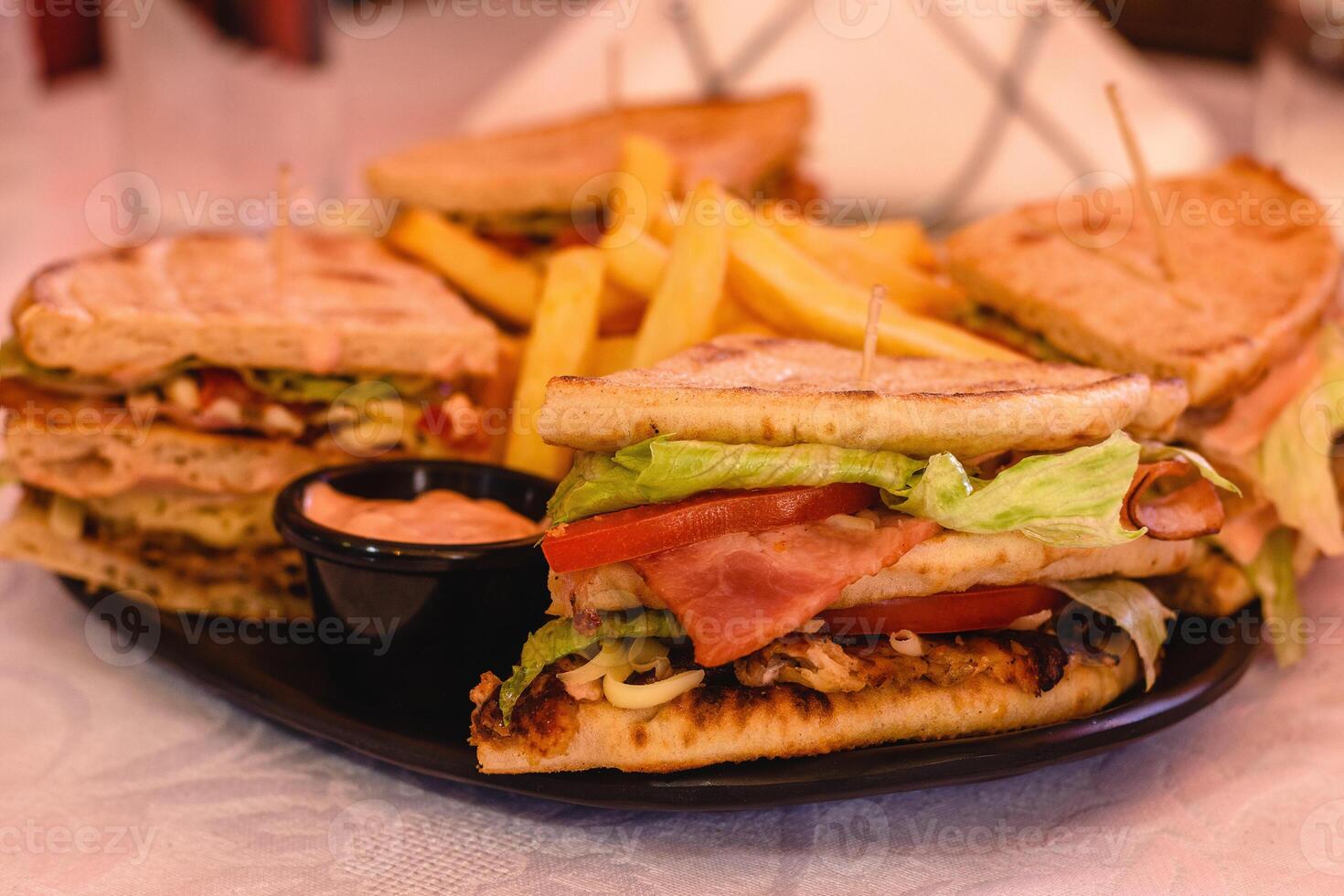 Verein Pita-Brot Giro Hähnchen mit Käse, Speck, Tomate, Kopfsalat, Soße serviert mit Fritten auf das schwarz Teller auf Weiß Hintergrund im griechisch Taverne. Tabelle Einstellung. Mittelmeer Küche. selektiv Sanft Fokus foto