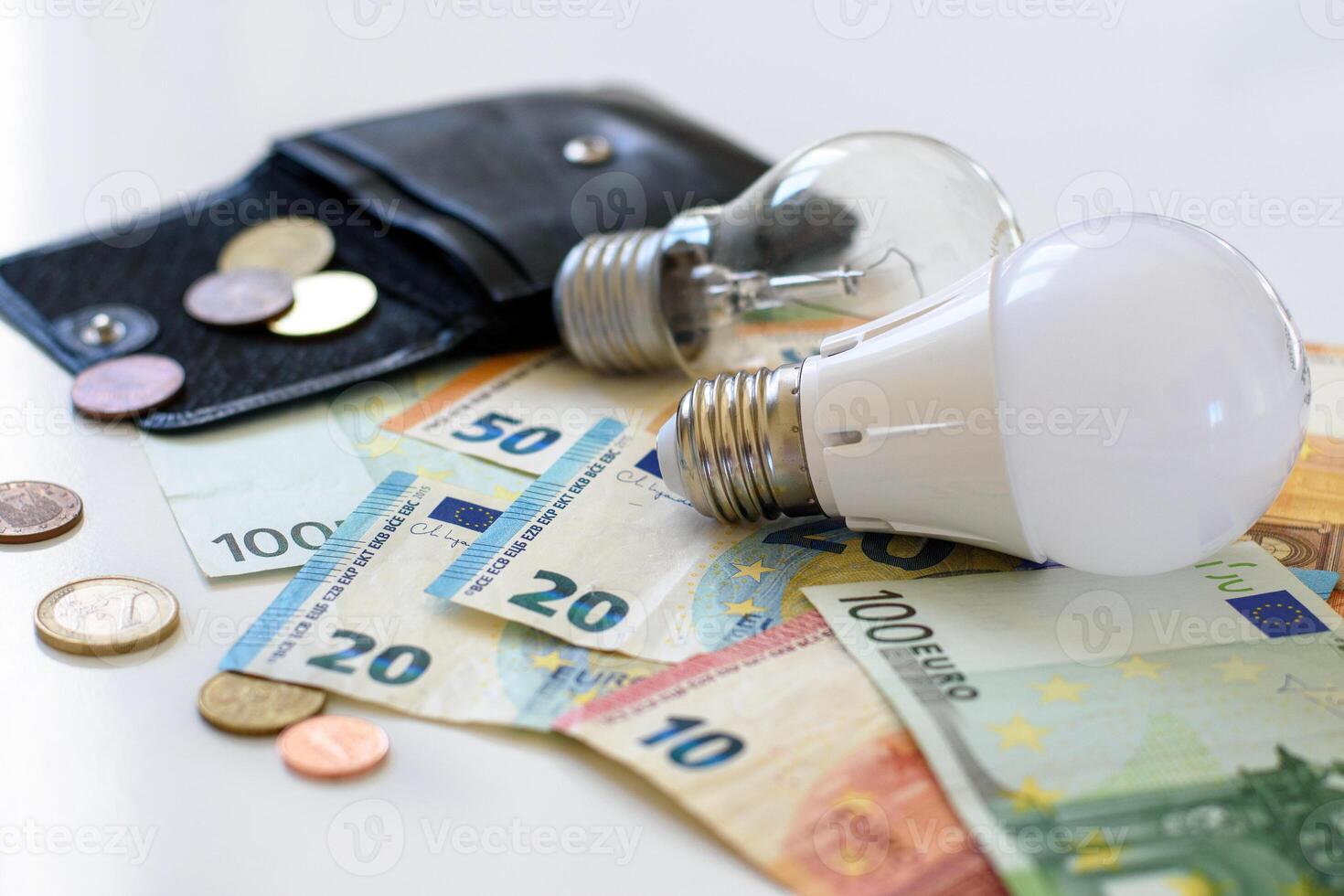 Licht Glühbirnen auf das Hintergrund von Euro Banknoten und schwarz Leder Brieftasche mit Münzen. speichern Geld durch mit Energie Ersparnisse Licht Glühbirnen. selektiv Fokus. Kosten von Elektrizität und teuer Energie Konzepte. foto