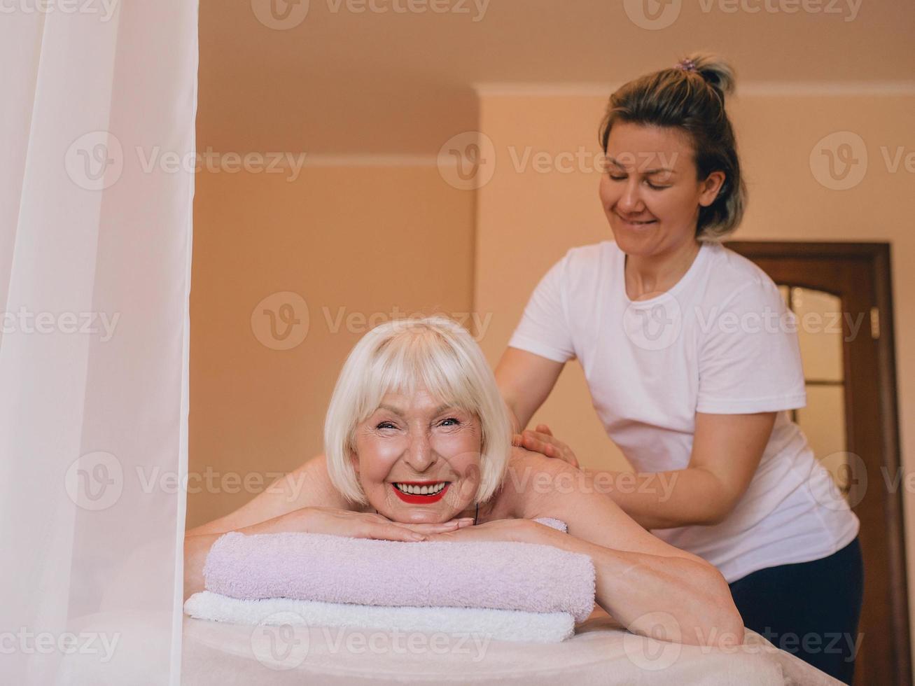 ältere kaukasische stilvolle frau mit grauem haar, die auf einer massage liegt. Anti-Age, gesunder Lebensstil, Massagekonzept foto