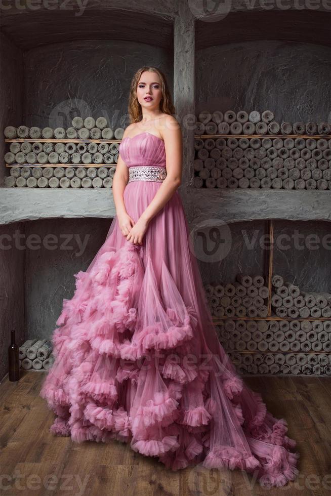 Porträt der jungen schönen Frau im langen rosa Kleid foto