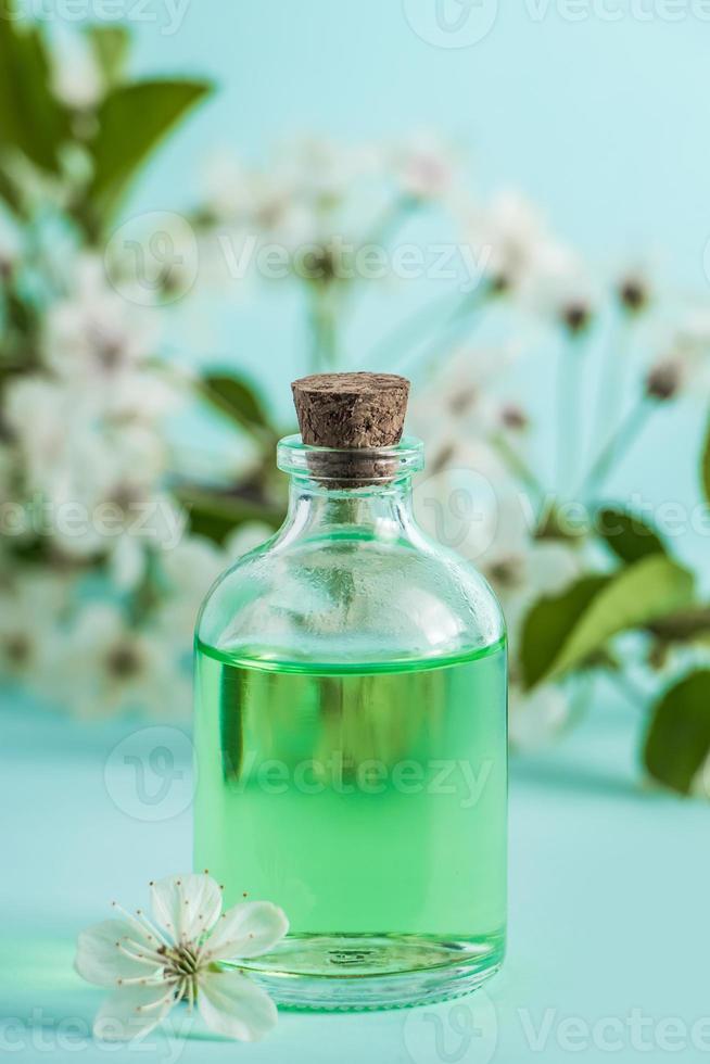 Flasche mit Naturkosmetiköl und Blumen auf blauem Hintergrund. foto