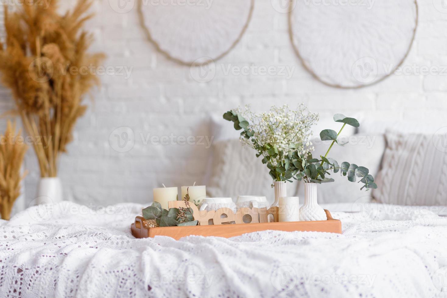 schöne Wohneinrichtung in Weiß- und Beigetönen, mit Traumfängern, Trockenblumen und einem Bett foto