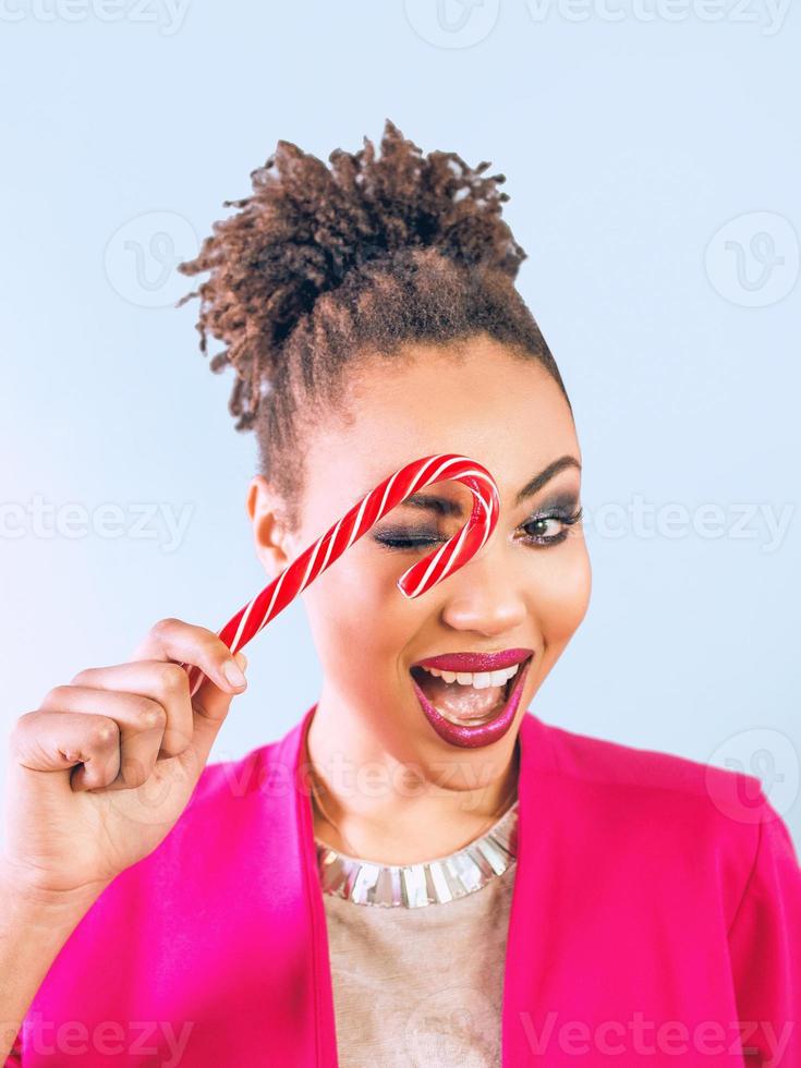 fröhliche und glückliche afroamerikanische Frau mit Zuckerstange. Weihnachten, Neujahr, Zucker, Glück, Ferienkonzept foto