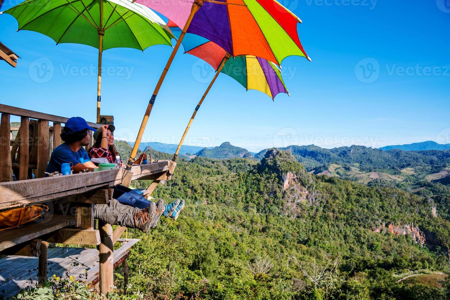 Touristen asiatisches Paar, das sitzt, isst Nudeln auf der Holzplattform und blickt auf die malerische Aussicht auf die wunderschönen Naturberge bei Ban Jabo, Mae Hong Son, Thialand. foto