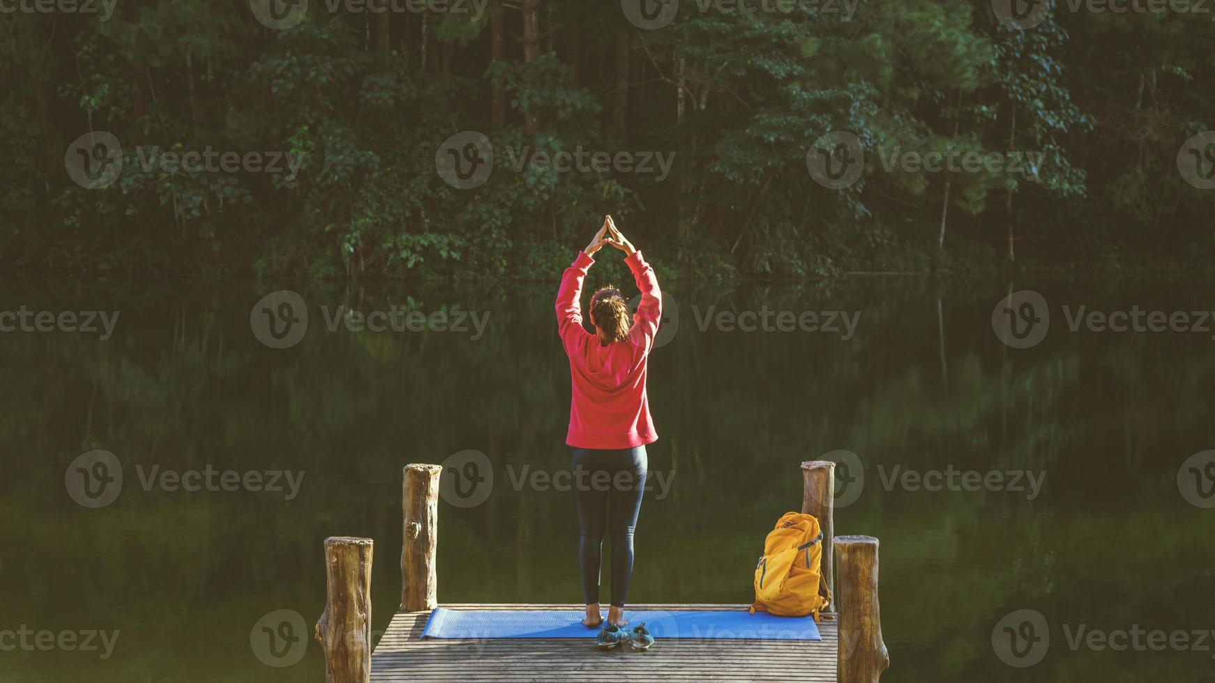 asiatische frauen entspannen sich im urlaub. spielen, wenn Yoga. auf dem berg, übung, spiel beim yoga auf der bambusbrücke neben dem see im nebel von pang ung, thailand. foto