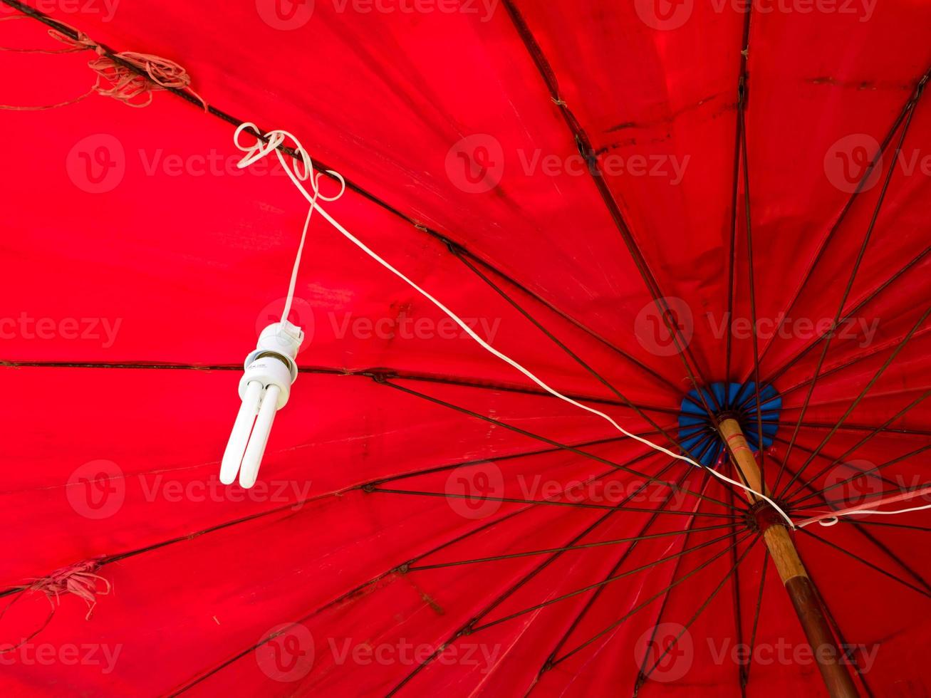 eine kompakte Leuchtstofflampe, die unter einem roten Regenschirm hängt foto