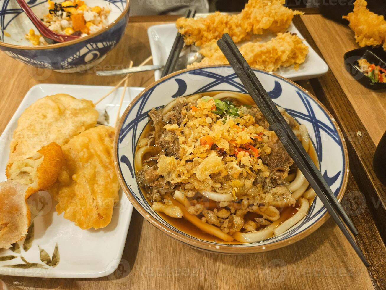 traditionell japanisch Nudel Suppe Niku Udon mit Rindfleisch Sukiyaki, Tempura, und geschnitten Frühling Zwiebel und Chili foto