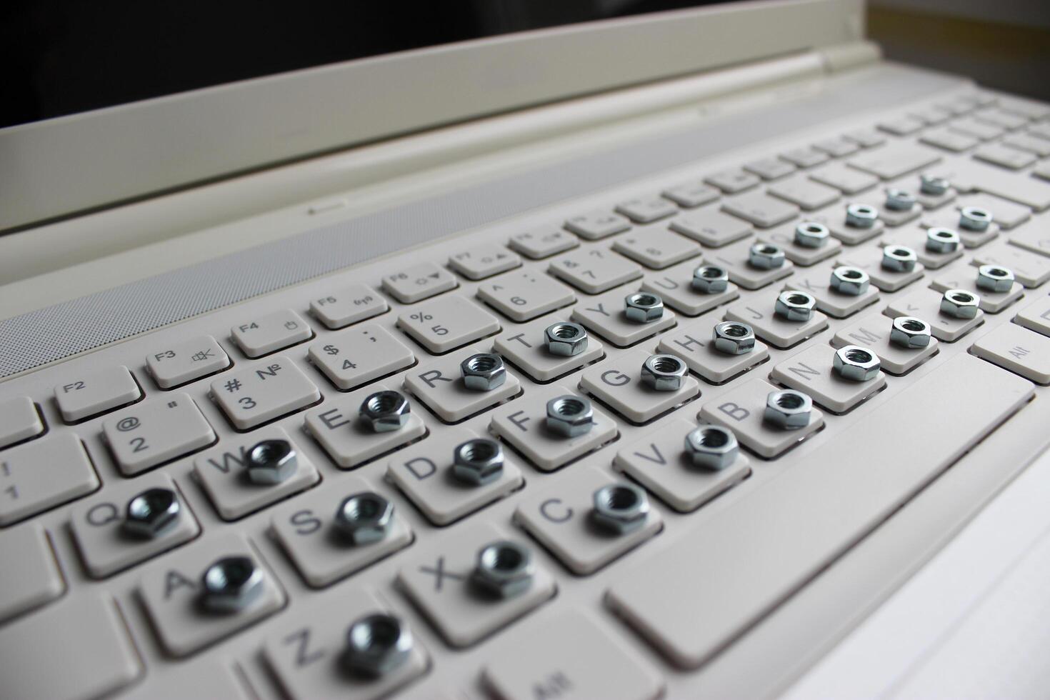 abgewinkelt Seite Aussicht von ein Computer Tastatur mit ein Eisen Nuss auf jeder Taste foto