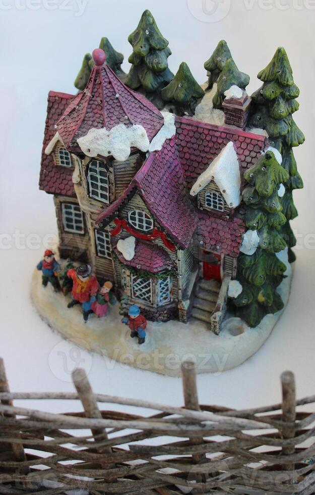 Spielzeug Haus auf das Schnee hinter ein Korbweide Zaun Diorama zum Kinder foto