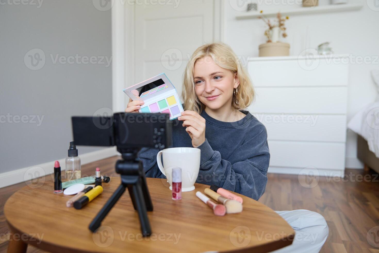 Lebensstil Blogger, Aufzeichnungen im ihr Zimmer, hat ein Kamera auf Kaffee Tisch, zeigt an Lidschatten Palette zu ihr Anhänger, tut bilden Lernprogramm, vlogger Arbeiten drinnen, schafft Inhalt zum Sozial Medien foto