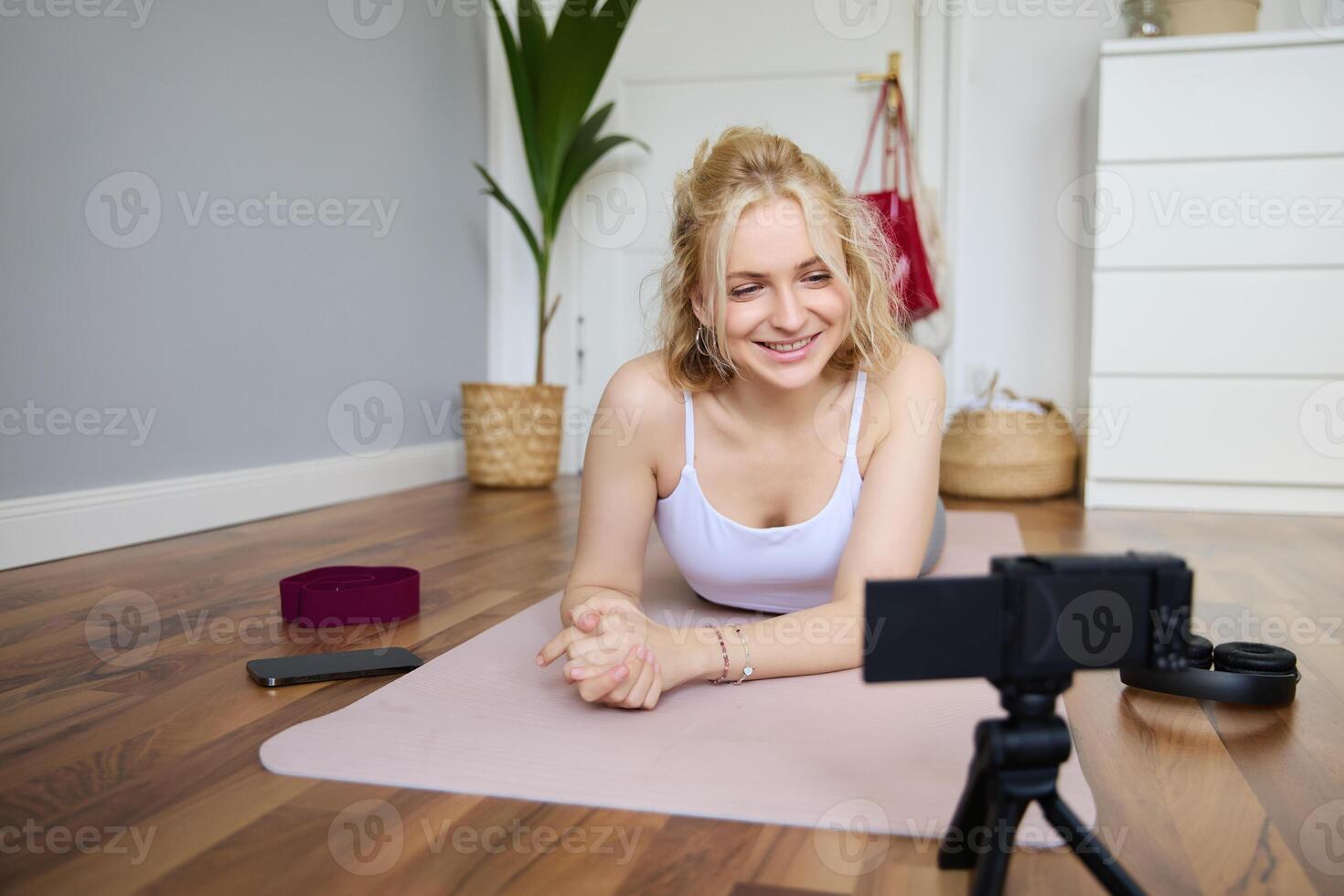 Porträt von jung Frau, Sport Vlogger, Fitness Lehrer Aufzeichnung von Sie selber zeigen trainieren Übungen, mit Digital Kamera, Lügen auf Yoga Gummi Matte foto