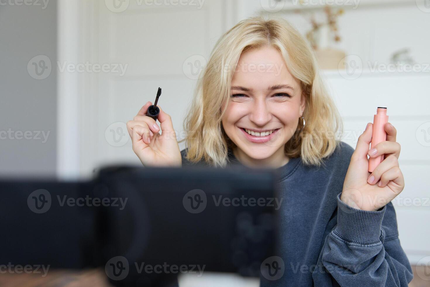 Porträt von Schönheit Blogger, Frau Aufzeichnungen auf Kamera im ihr Zimmer, zeigt an bilden Schönheit Produkte, Gespräche Über Kosmetika im vlog, macht Lebensstil Inhalt zum Anhänger auf Sozial Medien foto