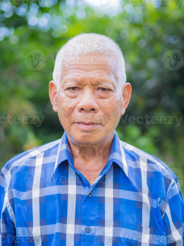 Senior Mann trägt ein Blau Hemd Stand im Garten foto