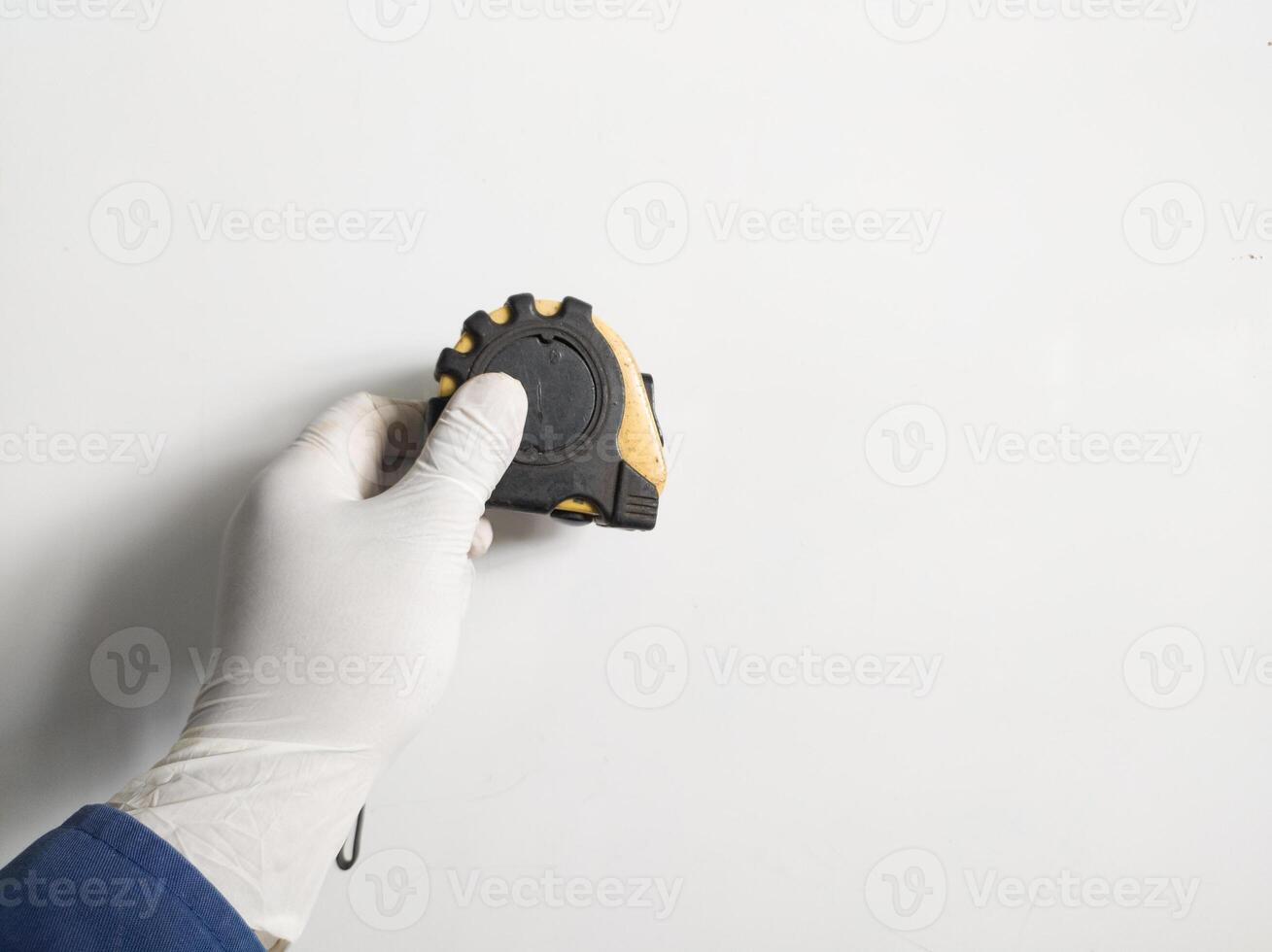 des Mannes Hand mit Handschuhe hält ein Stahl Messung Band Gelb abnd schwarz Farbe isoliert auf Weiß Hintergrund. foto