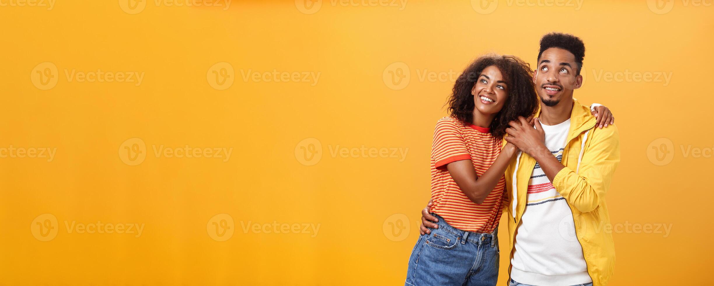 Paar von Liebhaber genießen Ausgaben warm Sommer- Abend zusammen Blick oben beim Sterne mit glücklich begeistert Ausdruck Sein im Liebe umarmen und ausdrücken warm romantisch Gefühle Über Orange Mauer foto