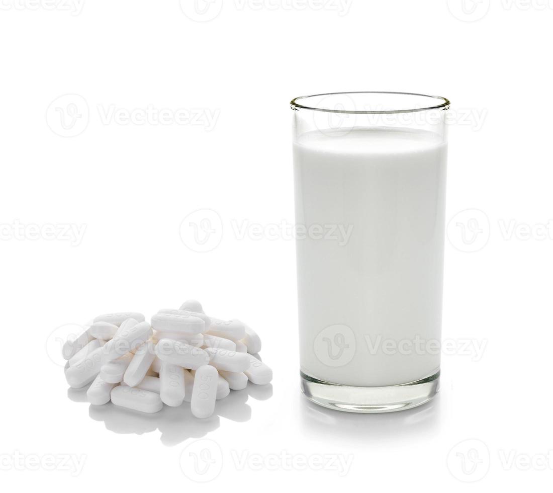 Pille und Glas Milch auf weißem Hintergrund foto