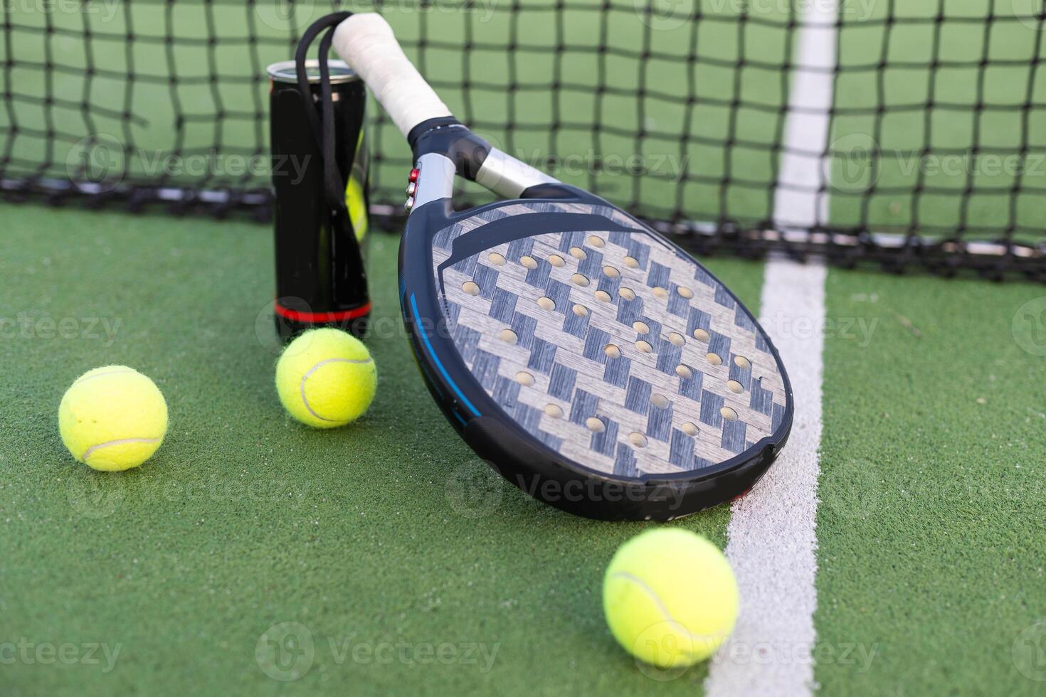 Gelb Bälle auf Gras Rasen in der Nähe von Padel Tennis Schläger hinter Netz im Grün Gericht draußen mit natürlich Beleuchtung. Paddel ist ein Schläger Spiel. Fachmann Sport Konzept mit Kopieren Raum. foto