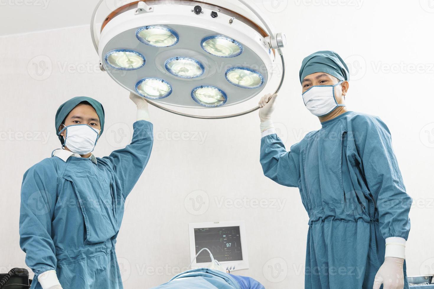 Assistenzchirurg, der Operationslampen im Operationssaal vorbereitet foto