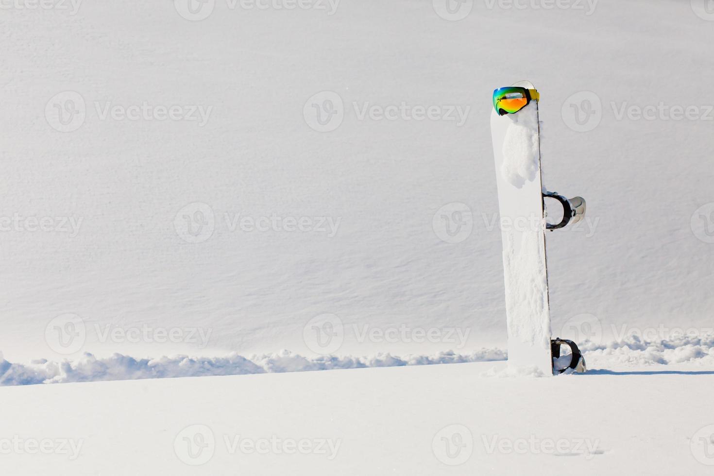 Snowboard- und Skibrille, die auf einem Schnee in der Nähe der Freeride-Piste liegt foto