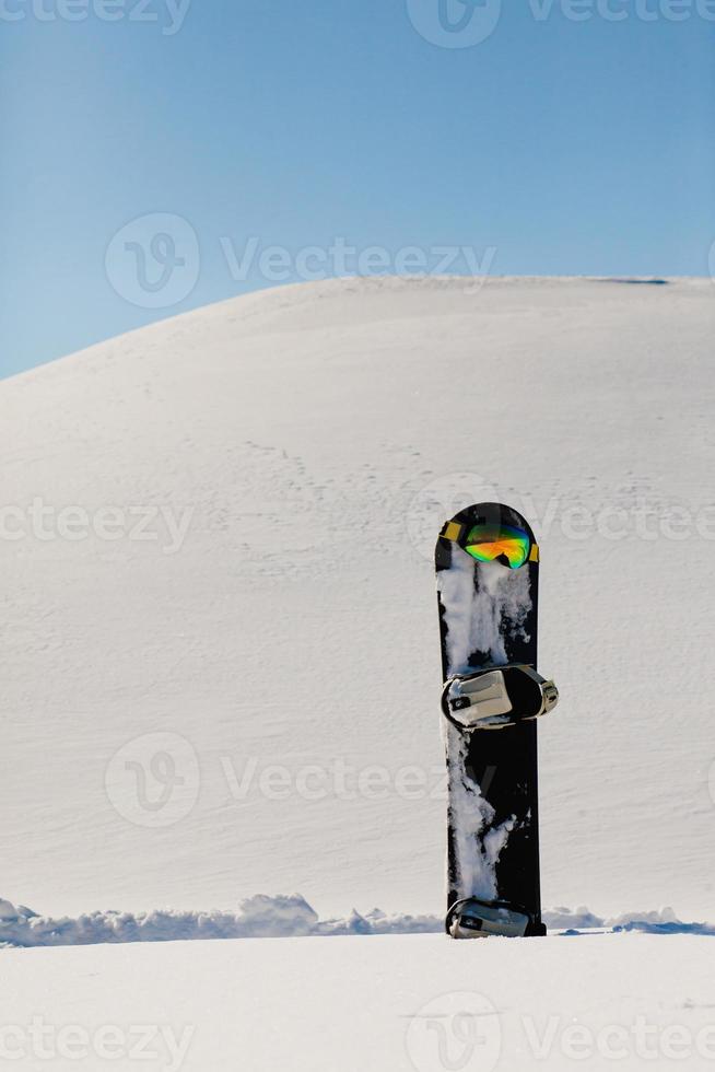 Snowboard- und Skibrille, die auf einem Schnee in der Nähe der Freeride-Piste liegt foto