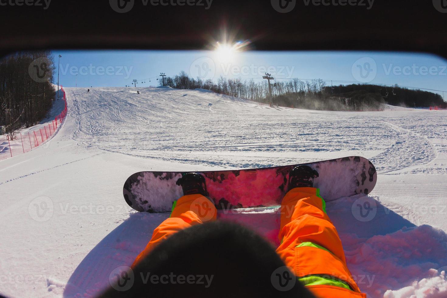 Sichtaufnahme eines männlichen Snowboarders, der auf dem Schnee sitzt foto