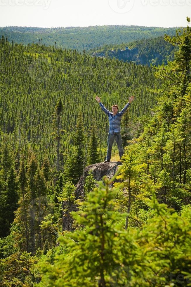 junger Mann auf einem Felsen mitten in der Natur foto