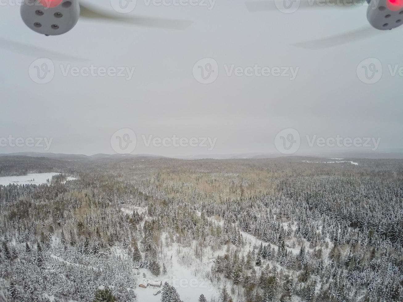 Quadcopter-Blick auf den Wald und die kleine kanadische Holzhütte im Winter. foto