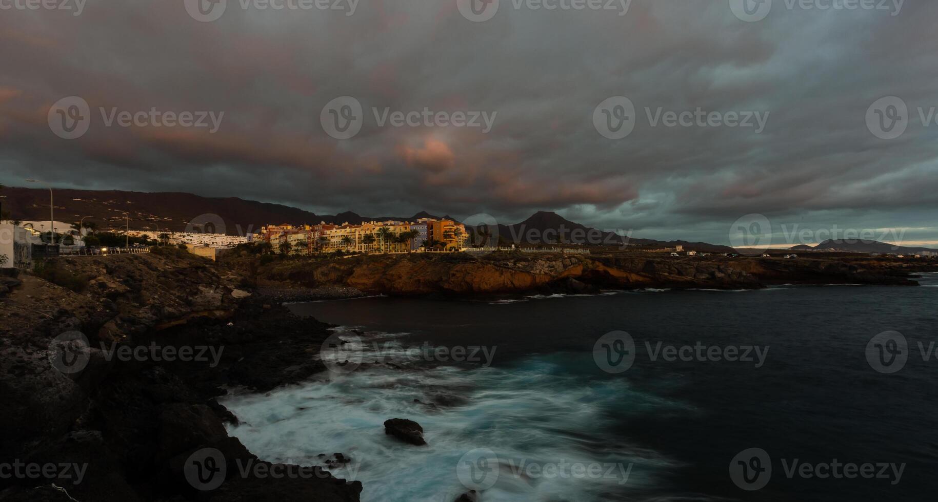 Panorama- Aussicht von das beleuchtet las Amerika beim Nacht gegen das bunt Sonnenuntergang Himmel mit Beleuchtung auf das Horizont auf Tenerife Insel, Spanien foto