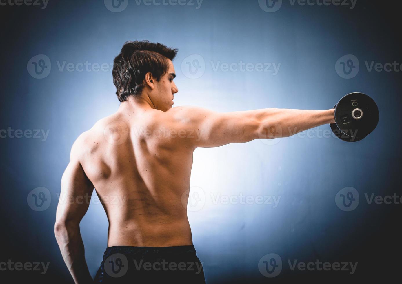 Sportler mit Hantel in ausgestreckter Hand foto