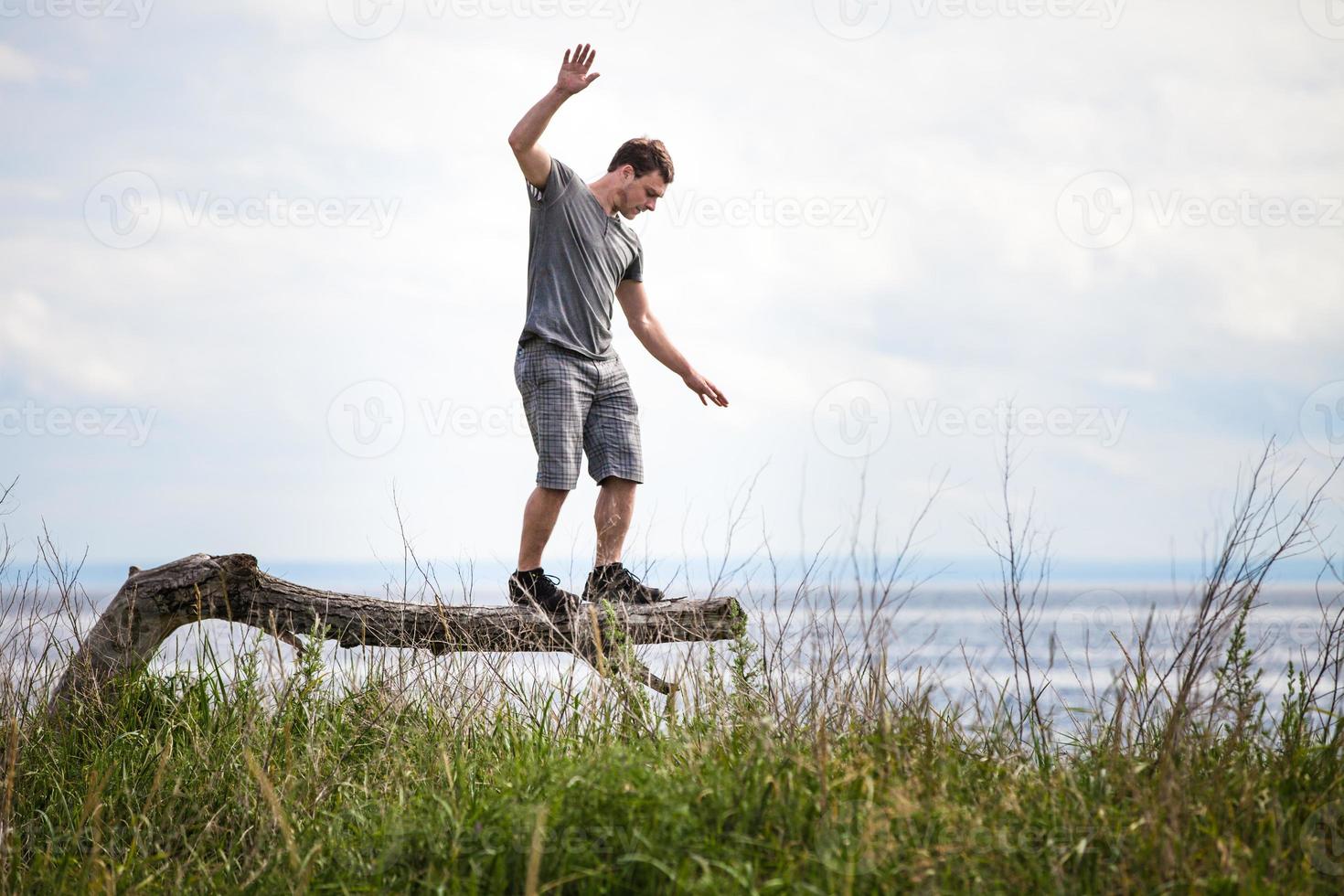 junger Erwachsener, der auf einem Baum im Urlaub balanciert foto