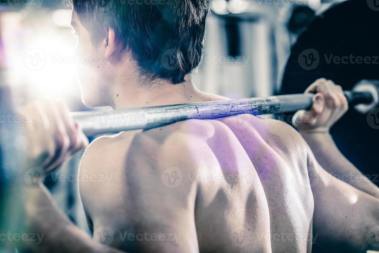 muskulöser Sportler mit schwerer Langhantel auf den Schultern foto