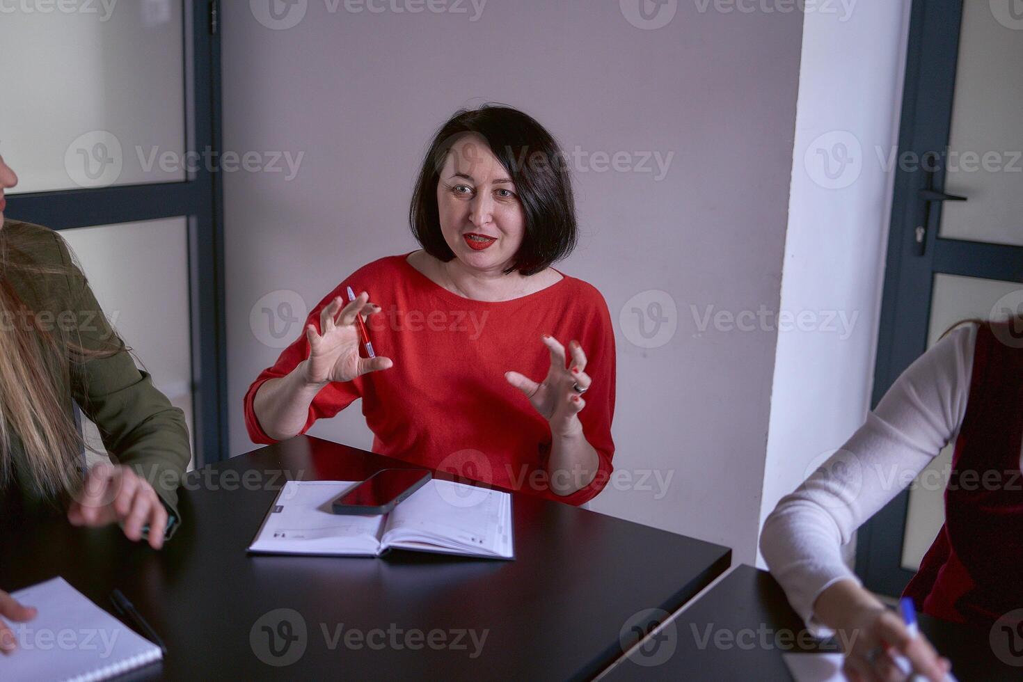 ein Frau im ein rot Sweatshirt Gesten emotional beim ein Treffen im das Büro foto