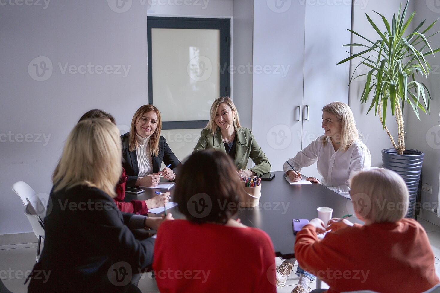ein Mannschaft von Sieben Frauen ist halten ein Treffen im das Büro foto