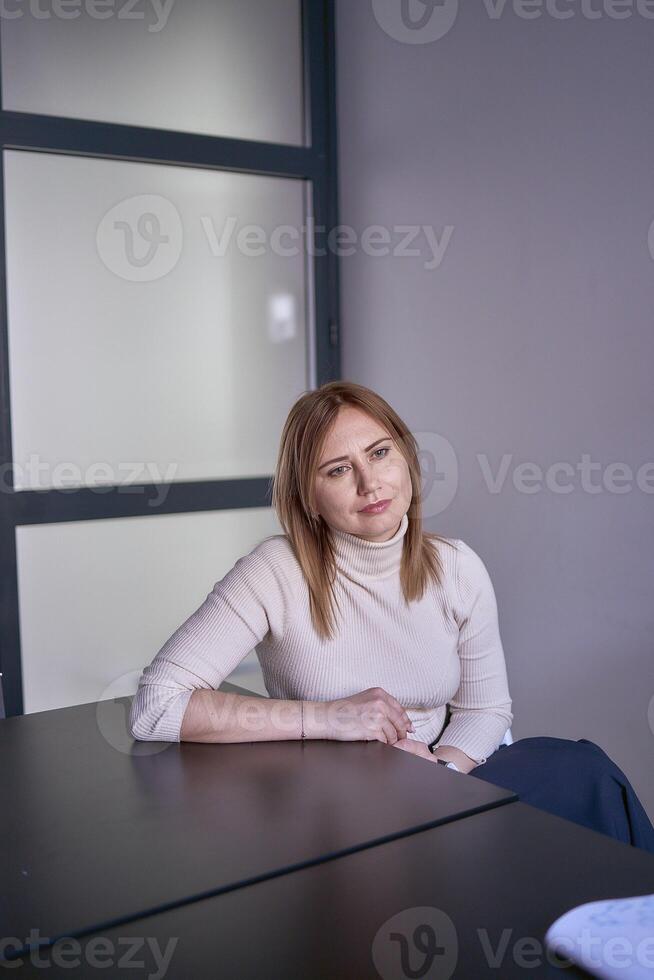 blond Frau im ein Licht Sweatshirt beim ein Treffen im das Büro foto